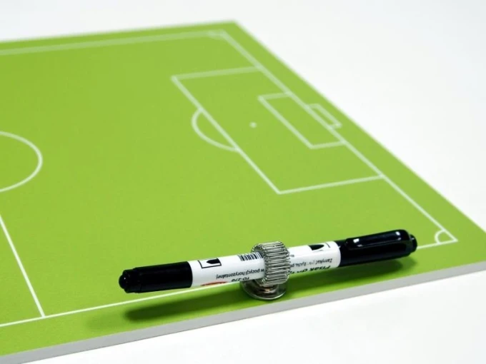 Tactical dry-erase coaching board for field hockey - Green surface with white lines and graphic design.
