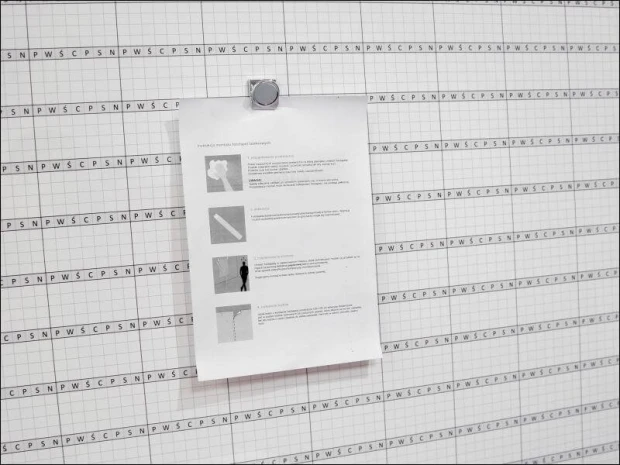 Metal magnetic clip - Office setup. Light-colored walls with a grid pattern in the background.