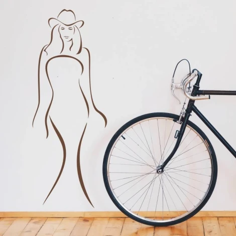 Decorative sticker of a female silhouette 2037 - Room setup with light-colored wall, wooden floor, bike nearby.