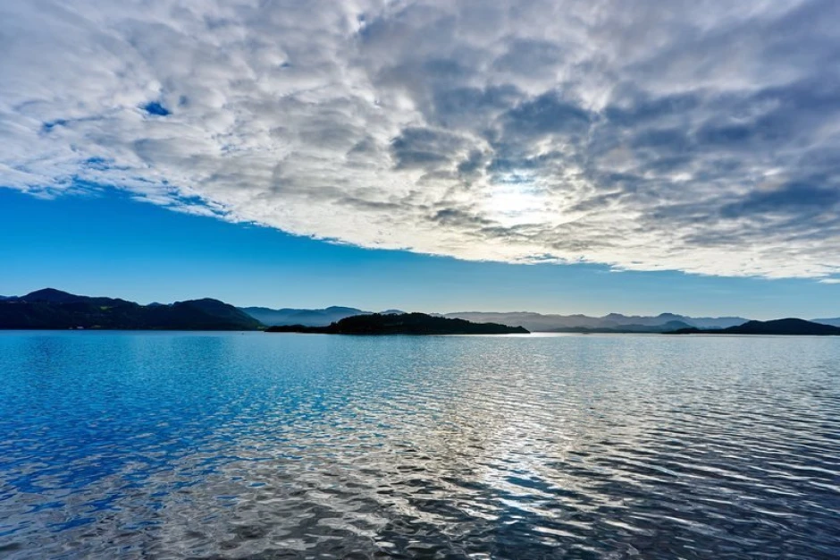 Wall mural of small islands seen from afar FP 1414 - Graphic design. Water reflects the sky, with islands and mountains in the background.