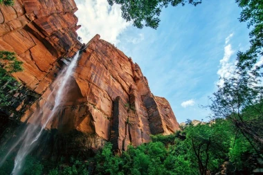 Waterfall wallpaper among red rocks FP 1622 - Graphic design. Water cascades from a high cliff, surrounded by nature.