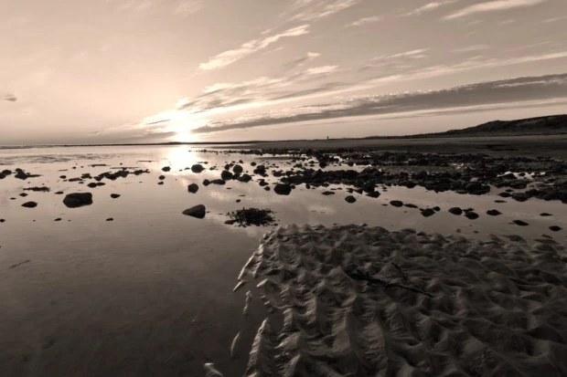 Wall mural of a sunset over the ocean, featuring waves, stones, and reflections. Design code: FP 1831.