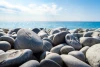 Beach pebble wallpaper FP 2017 - Graphic design. Smooth gray pebbles against a backdrop of blue water and sky.