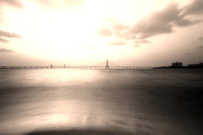 Wall mural of a bridge against a purple sunset, featuring water and clouds in soft hues.