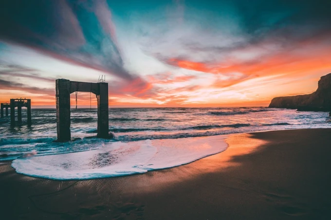 Wall mural of a bridge on an island FP 4424 - Graphic design. Bridge against a sunset backdrop with waves and clouds.