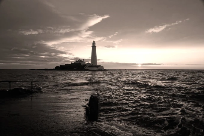 Wall mural of the last rays of sunlight over a lighthouse, graphic pattern with waves.