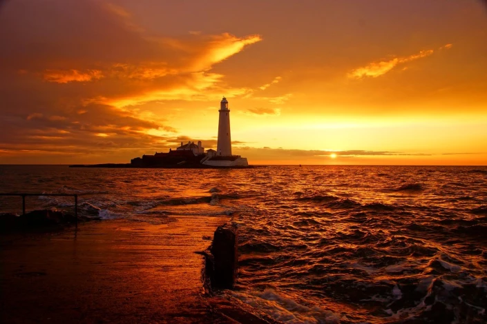Wall mural of the last rays of sunlight over a lighthouse - graphic design. Lighthouse against a sunset backdrop.
