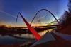 Wall mural of a solitary man on a modern bridge FP 4978 - Graphic design. Arch bridge over water at sunset.