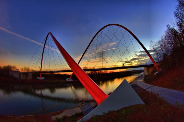 Wall mural of a solitary man on a modern bridge FP 4978 - Graphic design. Arch bridge over water at sunset.