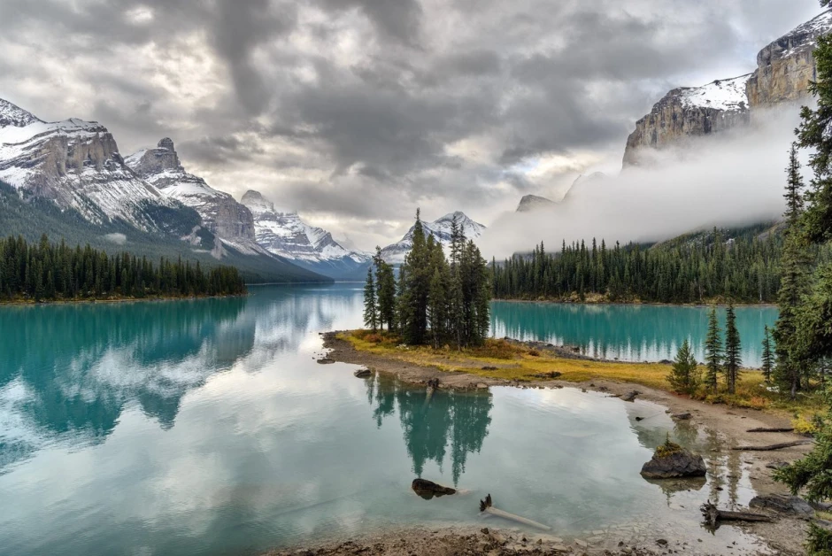 Wall mural of a mountain lake peninsula FP 5458 - Graphic design featuring water, mountains, clouds, and trees in various shades.