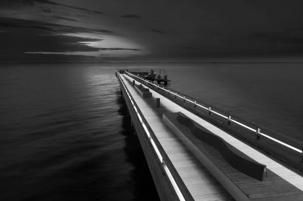 Wall mural of a pier at night FP 5444 - Styled in a modern interior with gray walls and minimalist furniture.