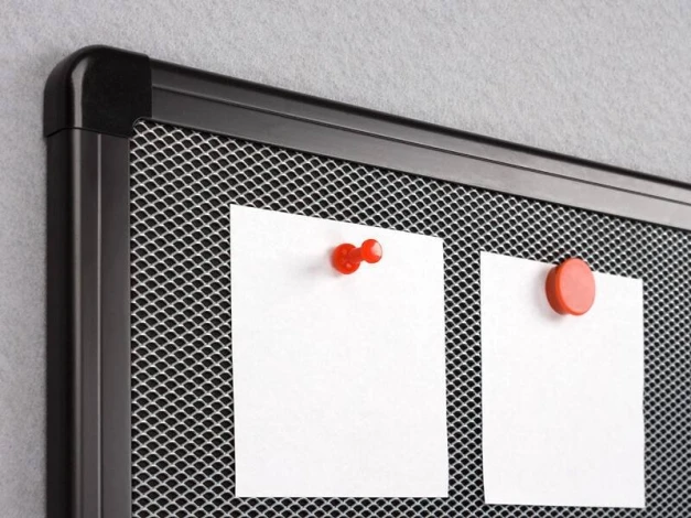 Magnetic pinboard with graphic design. Two white sheets attached to the mesh with magnets.