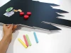 Chalkboard magnetic board for kids in the shape of a castle with cut-out towers and colorful designs.