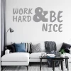 Wall sticker with the phrase "Work hard and be nice" - Living room decor. Light-colored walls, sofa with cushions.