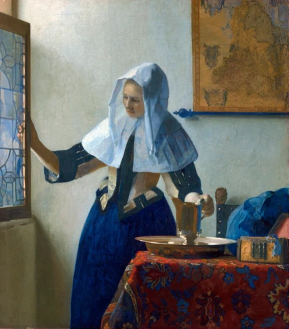 Reproduction of Young Woman with a Water Pitcher by Johannes Vermeer - Styled in a bright room with neutral walls.