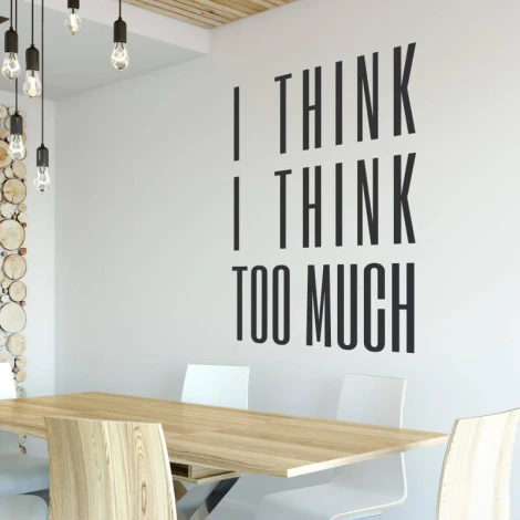 Wall sticker with the phrase "I think I think too much" - Dining room decor with light-colored walls and a wooden table.