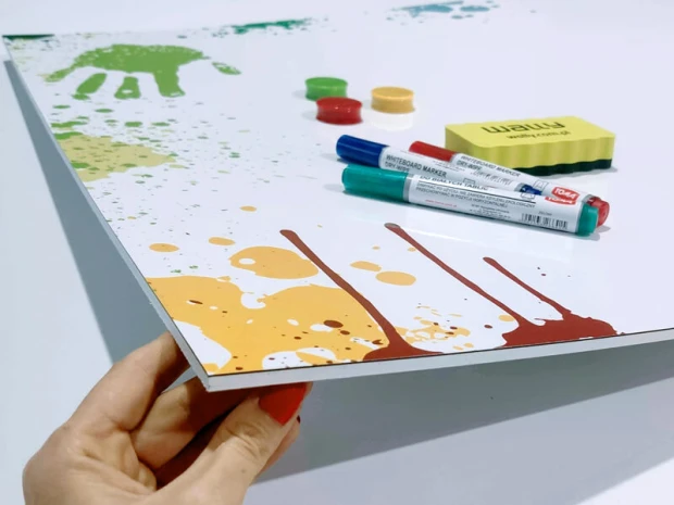 Magnetic whiteboard with a graphic design featuring colorful spots and handprints on a white background.