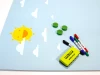 Dry-erase magnetic board for kids featuring sun and clouds design on a blue background with yellow accents.