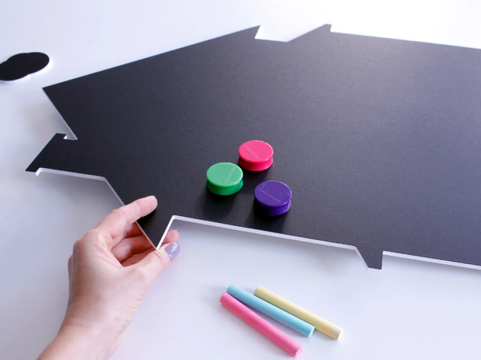 Chalkboard magnetic board in house shape with colorful magnets and chalk.