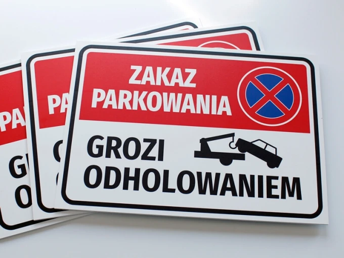 No Parking Sign, Towing Risk - Graphic Design. Rectangular sign with red background and white text.