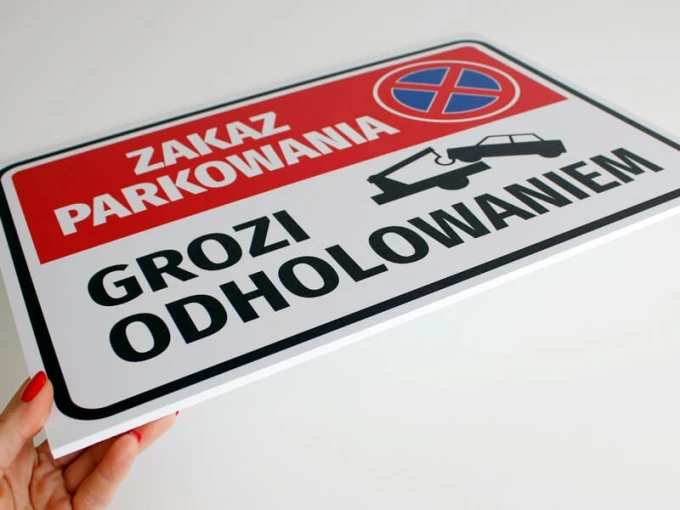 No Parking Sign, Towing Risk - Graphic Design. Rectangular sign with a red background and white text.