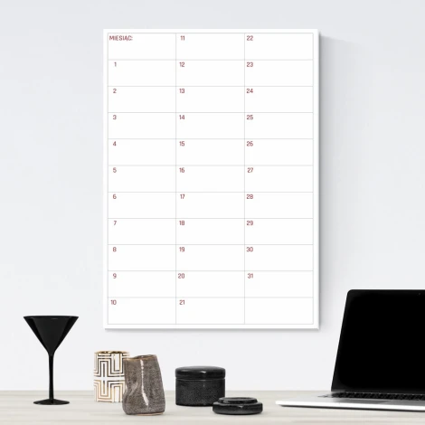 Magnetic dry-erase monthly planner board for office use. Light walls with dark-colored furniture.