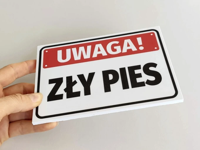 Warning sign, aggressive dog - Graphic design. Rectangular sign with a red background and large black letters.