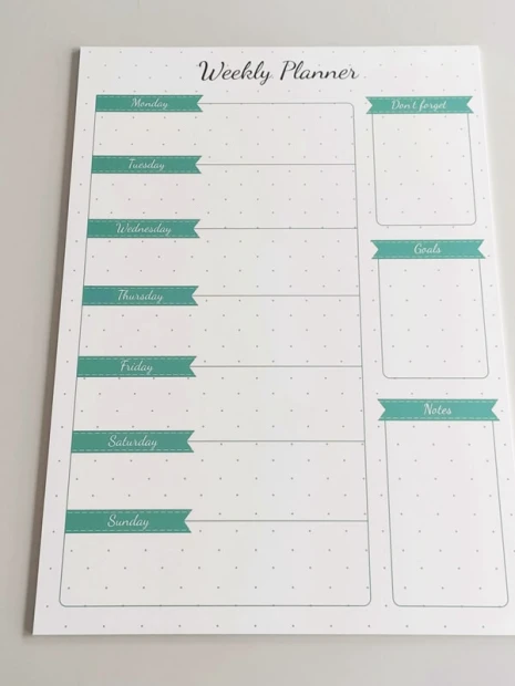 Weekly planner dry-erase board 407 - Graphic design. White surface with green ribbons and sections for days.