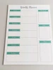 Weekly planner dry-erase board 407 - Graphic design. White surface with green ribbons and sections for days.