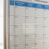 Freestanding magnetic whiteboard room divider with a graphic design featuring a weekly planner.