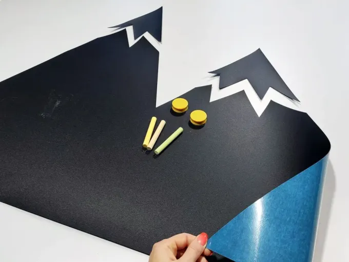 Chalkboard magnetic board for kids featuring a mountain design with white peaks, includes various chalk colors.