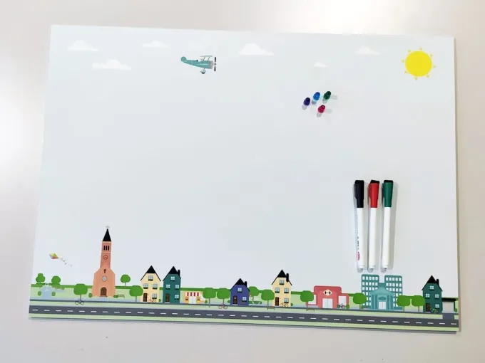 Magnetic dry-erase board for kids city design 495 - Features colorful buildings, an airplane, and clouds.