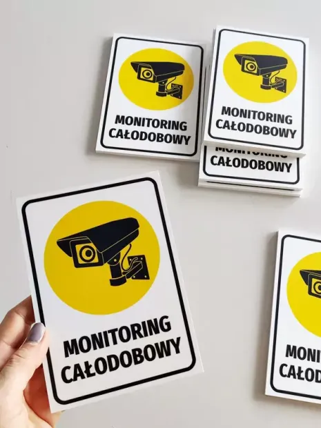 24/7 Monitoring Sign - Graphic Design. Yellow background with black camera icon and text.