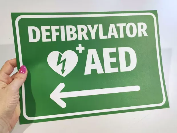 AED Defibrillator Sticker N561 - Graphic design with green background, white text, heart symbol, and arrow.
