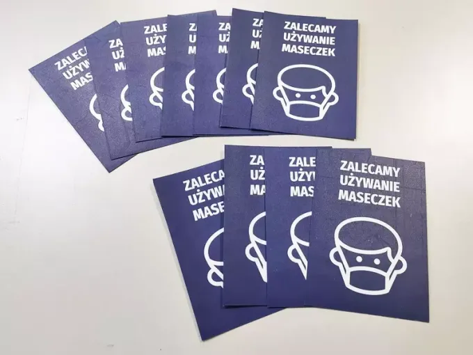Sticker recommending mask use - Graphic design. A white face illustration with a mask on a dark background.