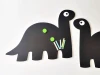 Chalkboard magnetic board for kids featuring dinosaur design with two rectangular dinosaurs and large eyes.