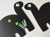Chalkboard magnetic board for kids featuring two black dinosaurs with white eyes and chalk.