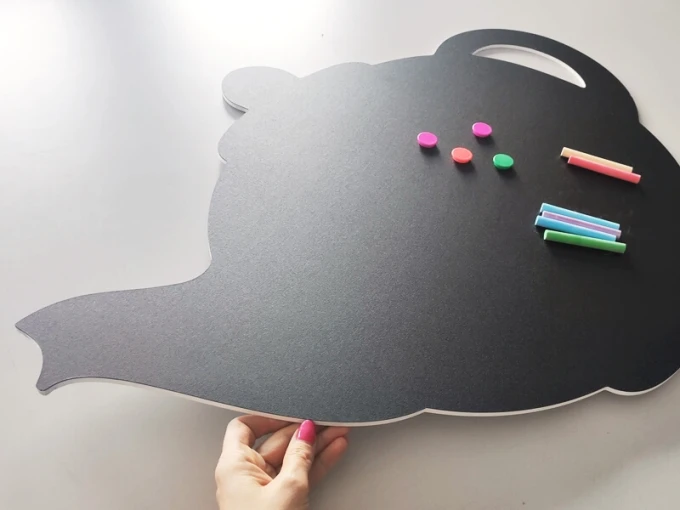Chalkboard magnetic board for kitchen in teapot shape with colorful magnets and chalks.