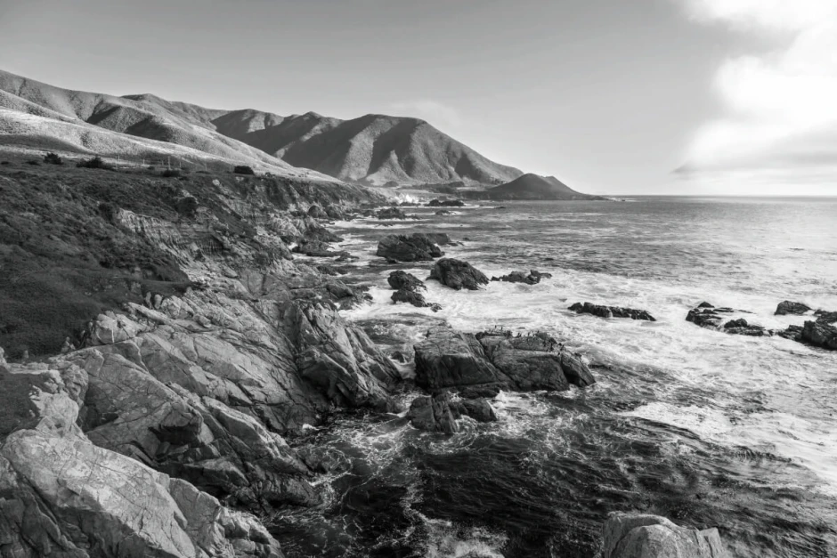 Wall mural rocky sea shore FP 6446 - Graphic design featuring visible rocks, waves, and mountains in the background.