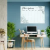 Weekly planner whiteboard with leaf design for office decor. Blue walls, light furniture, and plants.