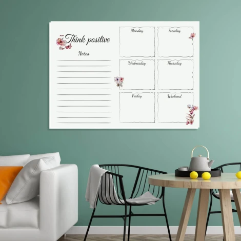 Weekly planner dry-erase board with floral design, styled in a green wall living room with black furniture accents.