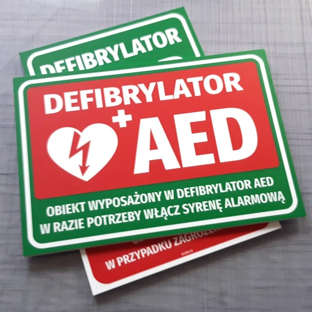 AED Defibrillator Information Sign - Rectangular sign with red background, white text, and symbol.