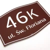 Building plaque with address and number - Graphic design. Simple shape, brown background with white letters.