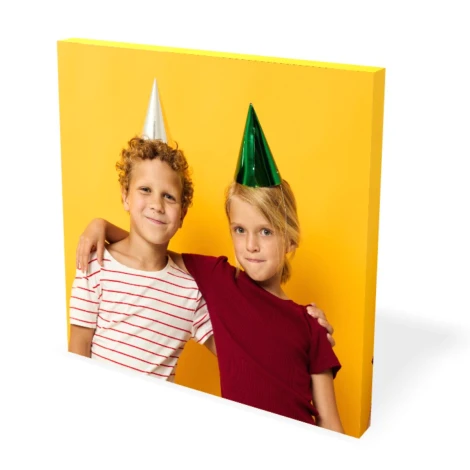 Canvas print 50x50 cm - Graphic design. Two children in birthday hats on a yellow background.