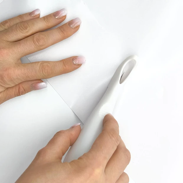 Safe media cutting knife - Graphic design. Hand holding the knife on a white background, cutting through material.