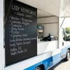 Chalkboard menu with artisanal ice cream flavors – setup in a mobile ice cream truck. White and blue food truck, hand-written flavors and prices, bright and minimalist interior.