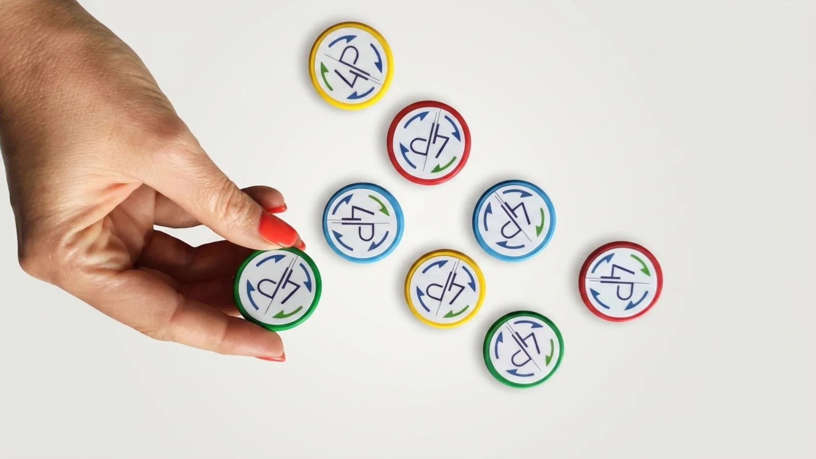 A hand holding a round magnet printed with a logo next to a set of coloured magnets